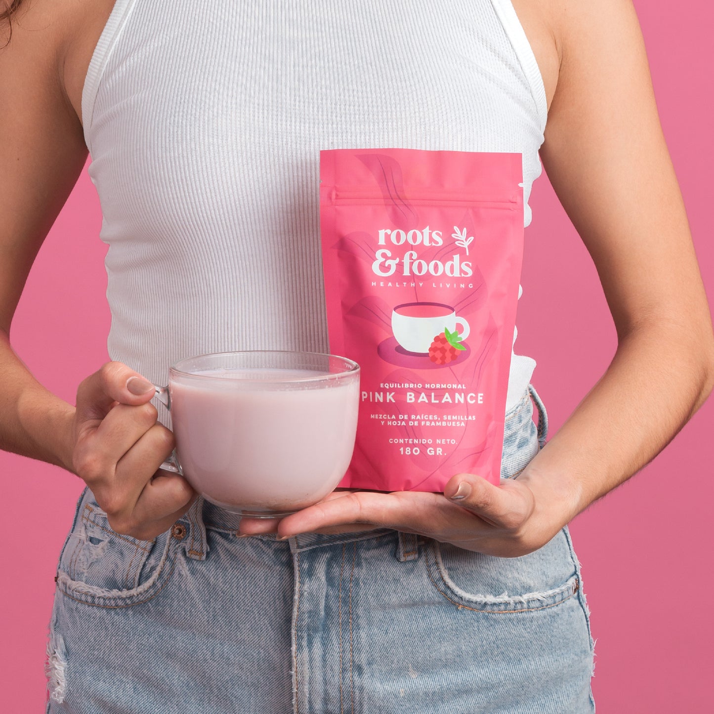 el torso de una mujer joven mostrando en sus manos un paquete de pink balance y una taza con bebida rosa pastel
