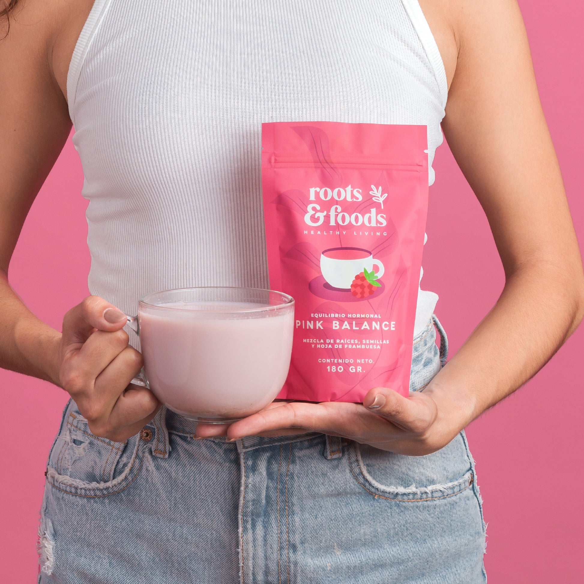 el torso de una mujer joven mostrando en sus manos un paquete de pink balance y una taza con bebida rosa pastel